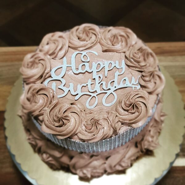 A birthday cake with chocolate frosting and a happy birthday sign.