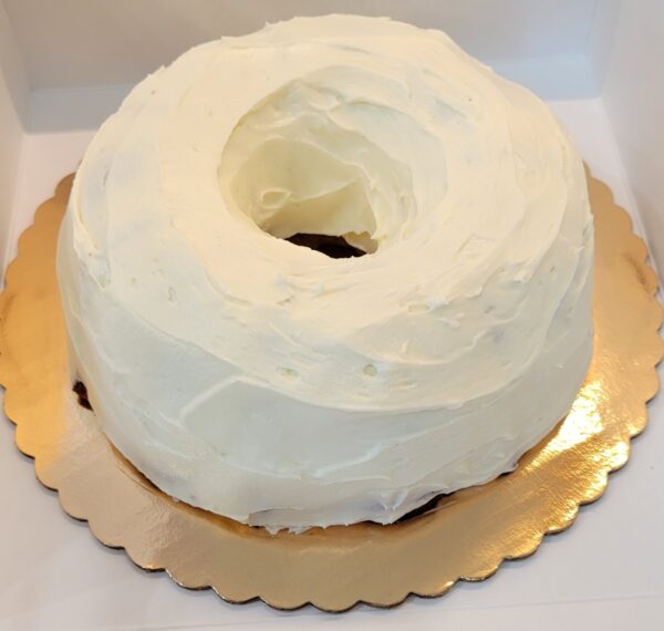 A white cake on a gold plate with a large ring of frosting.