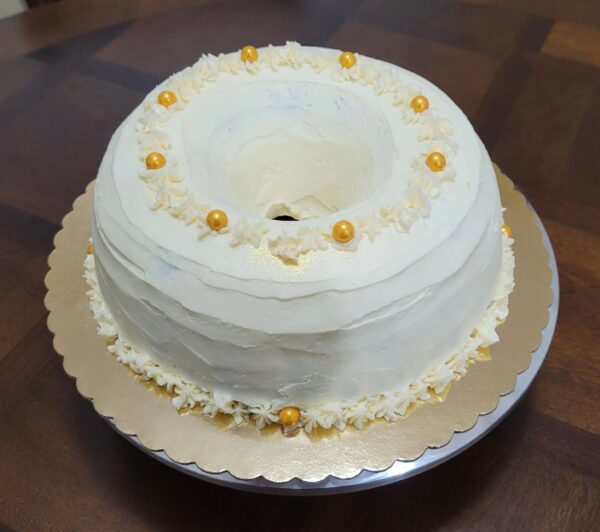 A white cake with gold decorations on top of it.