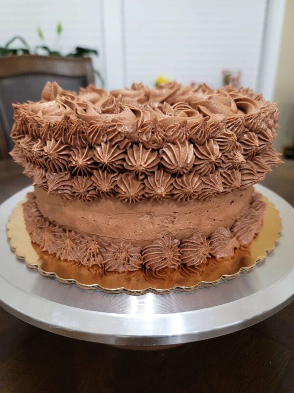 A large chocolate cake sitting on top of a metal plate.