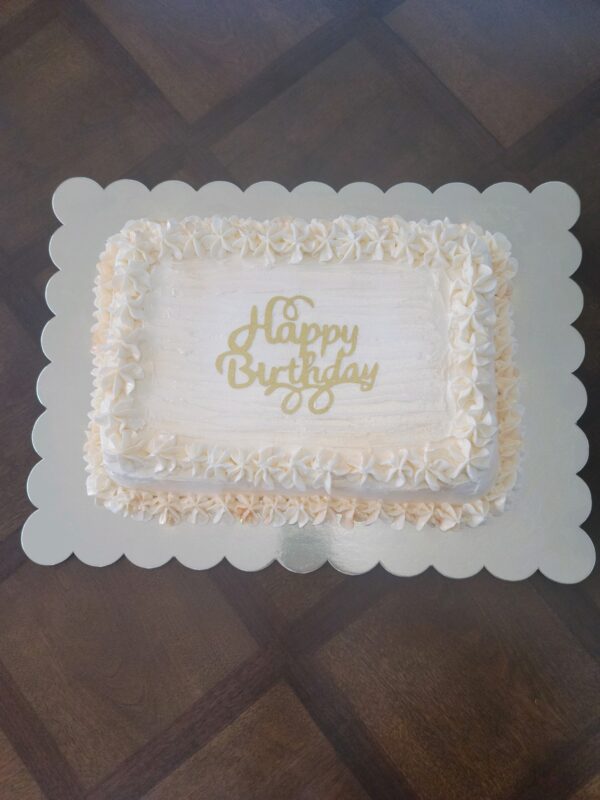 A white sheet cake with a happy birthday sign on top.